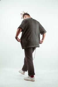 A man walks away, holding up his shirt.